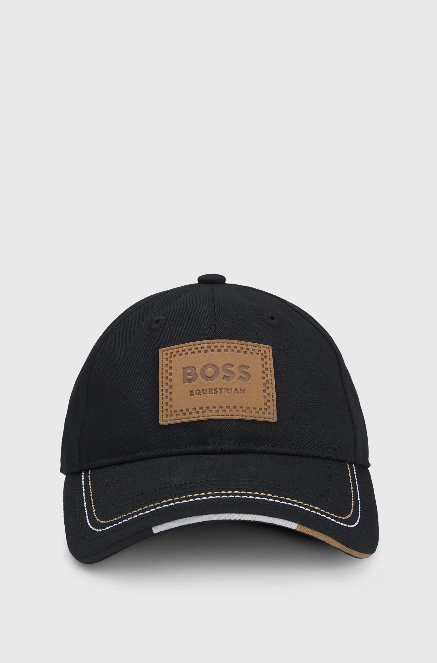 Black | A black baseball cap with a brown rectangular BOSS Equestrian patch on the front, featuring white contrast stitching along the brim, photographed on a light gray background.