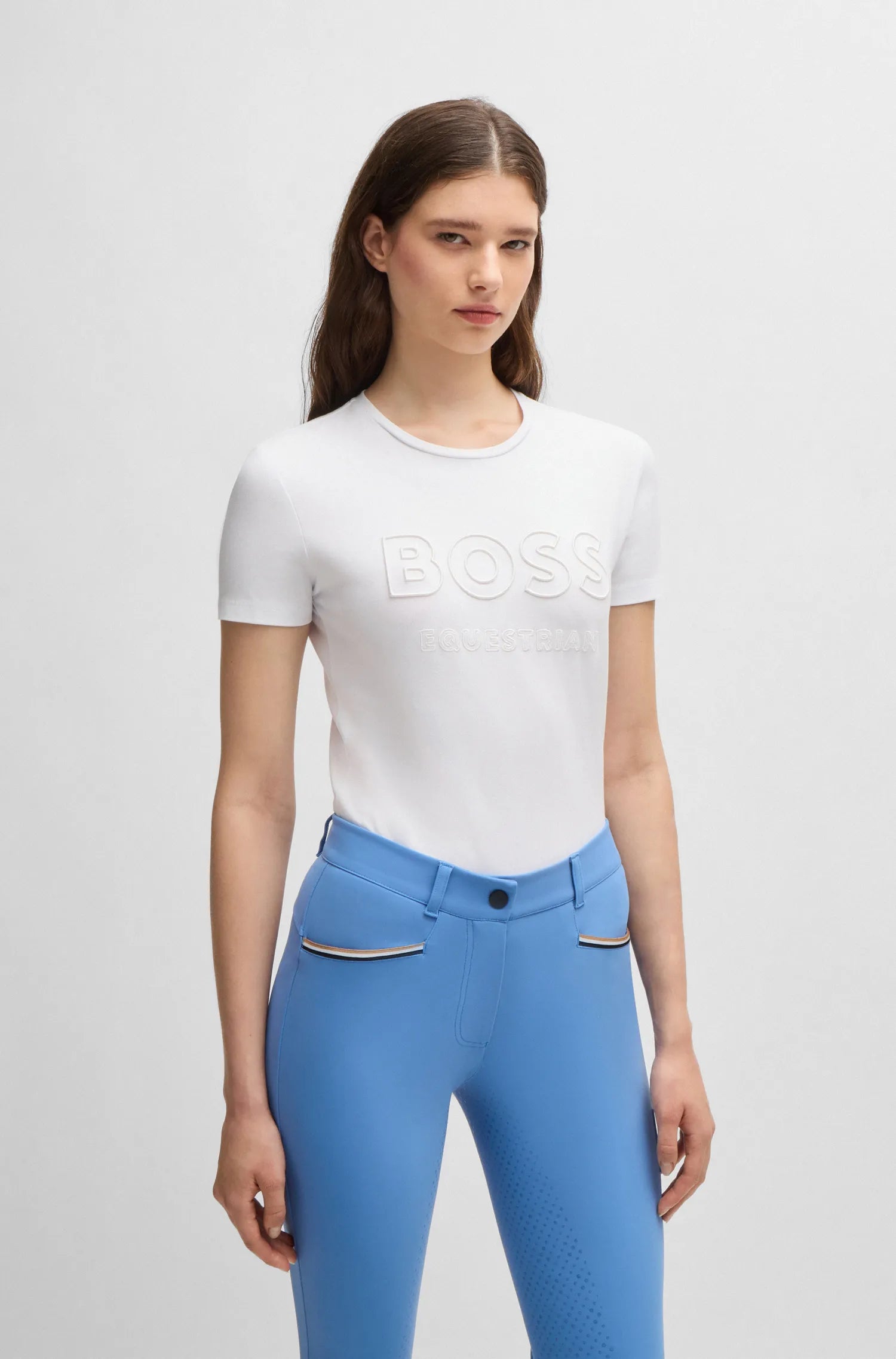 White | A model wearing a white short-sleeve BOSS T-shirt with a tonal embroidered logo and light blue fitted pants, standing against a light gray studio background.