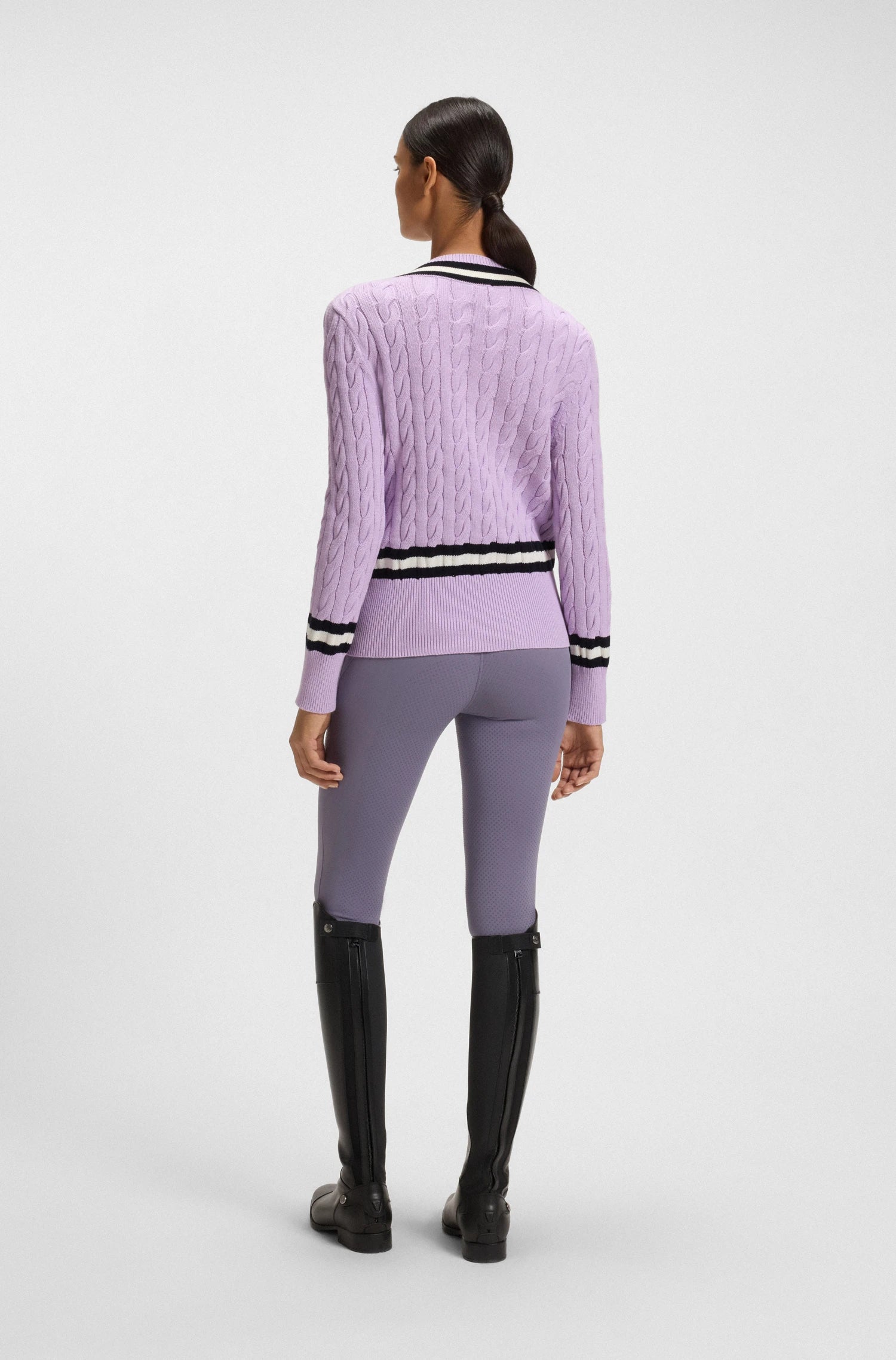 Orchid | Person wearing a purple sweater and leggings with black boots on a white background